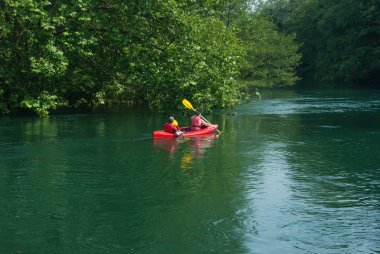 Kadın ve erkek üzerinde Adda Nehri üzerinde kırmızı bir kayık kürek