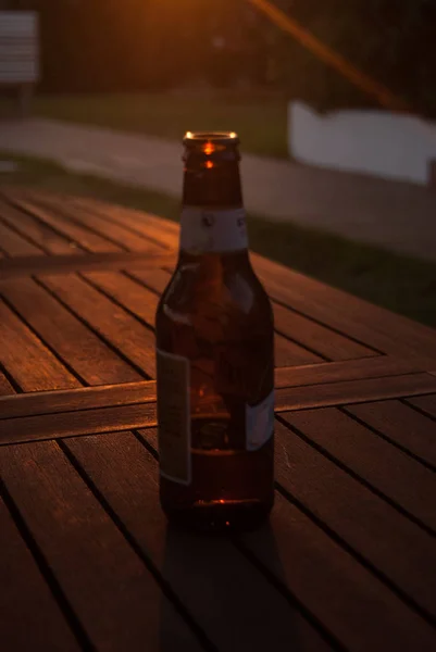 用一瓶啤酒照亮夕阳的一张桌子 — 图库照片