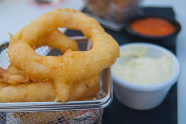 Close-up masada beyaz ve kırmızı soslu kızarmış kalamar halkaları