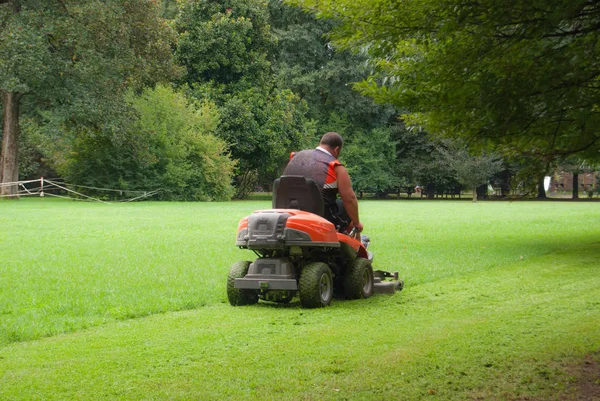 Adam bir çim biçme makinesi üzerinde otururken iş başında