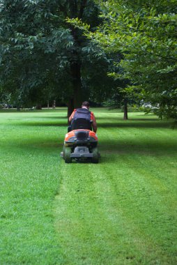 Adam bir çim biçme makinesi üzerinde otururken iş başında