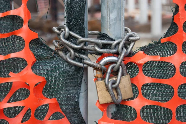 Padlock on a metal gate and plastic nets in an area of under construction