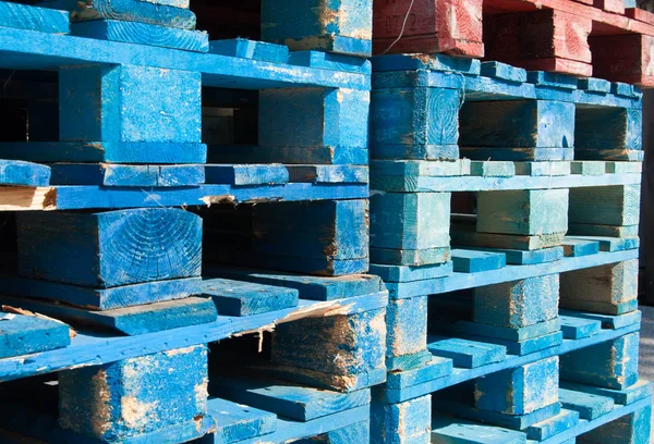 Colored pallets stacked on top of each other on the ground