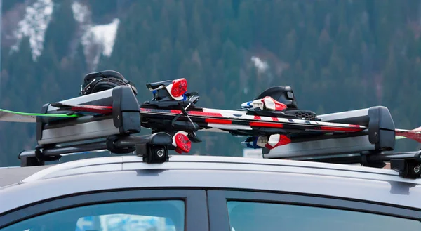 Arabanın çatısında iki çift kayak ve bir snowboard.
