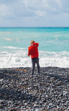 Bir çakıl plaja denizde bir kış günü sırasında çekerek çocuk