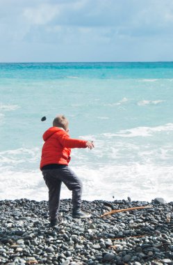 Bir çakıl plaja denizde bir kış günü sırasında çekerek çocuk