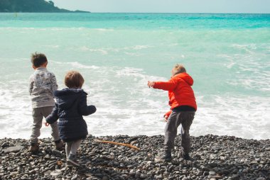 Üç çocuk çakıl plajdan denize bir kış günü sırasında çekerek