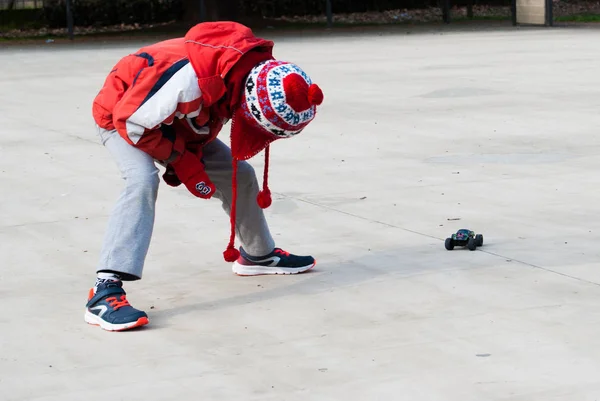 Little boy with open legs acting as a tunnel for his toy car