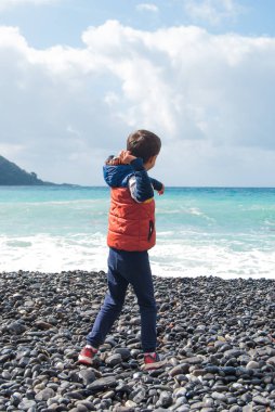 Bir çakıl plaja denizde bir kış günü sırasında çekerek çocuk