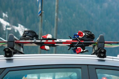 Arabanın çatısında iki çift kayak ve bir snowboard.