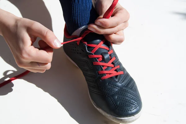 Closeup of hands of a child tying a soccer shoe on white backgro — Stock Photo, Image