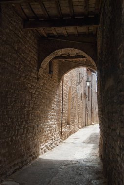Gubbio kasabasında bir kemer ile görülen dar ve boş sokak