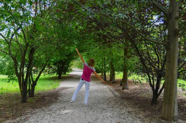 Bir kız birçok yeşil ağaçlar ile kir geçitte dengeli