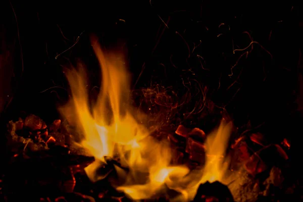Una hermosa textura horizontal de un fuego ardiente sobre un fondo negro con chispas —  Fotos de Stock