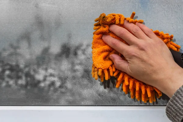 Bir kadın bir pencere turuncu sünger ile yıkar