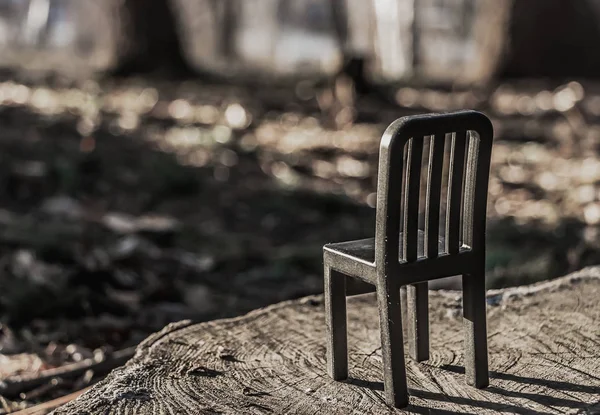 一个美丽的小玩具黑色塑料椅子是在一个模糊的棕色自然木制背景与阴影和波克棕色光 — 图库照片