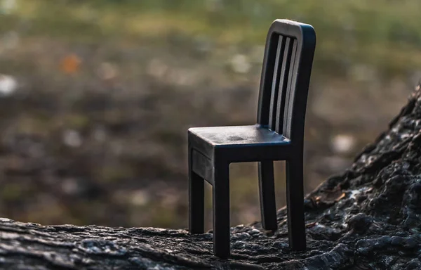 公园里一个模糊的背景上有一把漂亮的黑色小玩具塑料椅子 — 图库照片