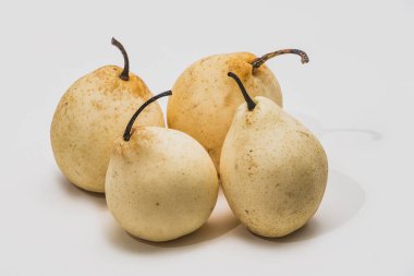 Beyaz bir arka plan üzerinde dört güzel sarı Nesha armut vardır