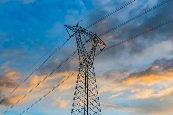 A power line is on the blue sky background with pink clouds at the sunset