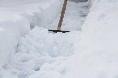 Sarı bir ahşap saplı siyah bir kürek kışın yola gelen temiz beyaz kar için kullanılır