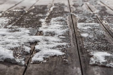 Kış aylarında bulanık kahverengi ahşap panoları arka plan üzerinde buz ve bokeh ışık ile beyaz kar küçük bir kar yağışı bir doku