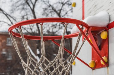 Kış aylarında bahçede çocuk oyun alanında beyaz halat net ve beyaz kar ile güzel bir kırmızı basketbol çember
