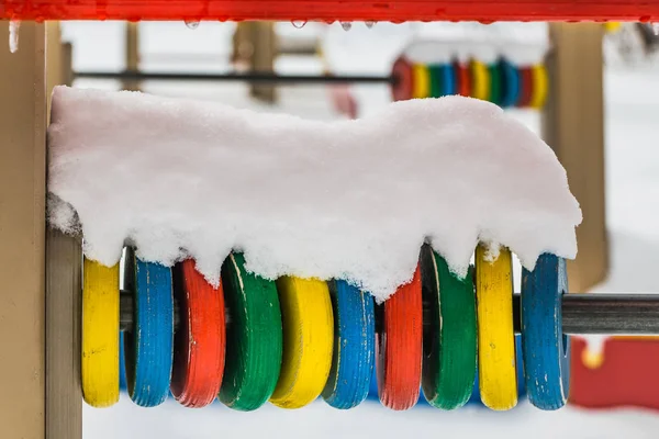 Gruppe mehrfarbiger Holzringe zum Zählen mit weißem Schnee auf dem Spielplatz für kleine Kinder im Winter — Stockfoto