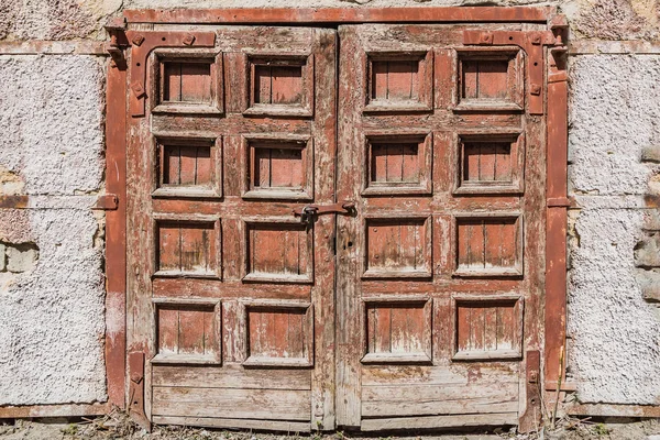 Старі ретро шорсткі дерев'яні пофарбовані коричневі подвійні двері з замком і фрагментом старої оштукатуреної стіни з голими цеглинами — стокове фото