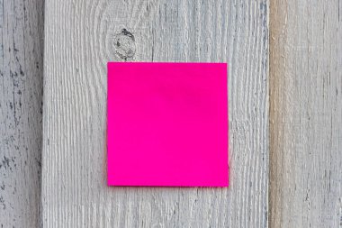 Fotokopi alanı olan kare pembe ya da kırmızı bir kağıt gri ahşap bir çitte asılı. Yatay