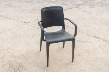 Gri arka planda plastik siyah bir sandalye.