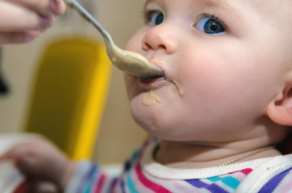 A mãe dá a comida de bebê de uma colher — Fotografia de Stock