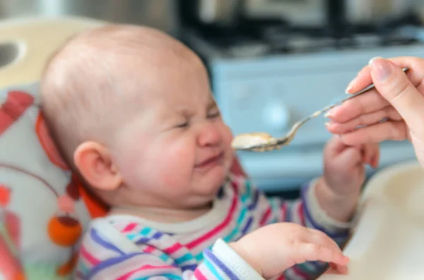 A mãe dá a comida de bebê de uma colher — Fotografia de Stock