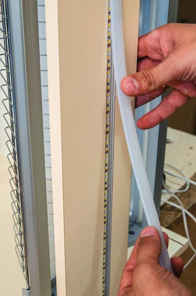 Installing an LED strip in an aluminum profile on a kitchen set closeup