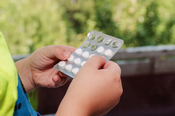 Ein kleines Kind hält einen Teller mit Tabletten in den Händen — Stockfoto