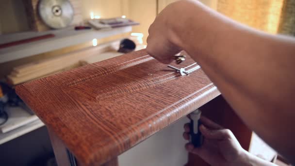 Master carpenter installs the furniture handle on the wooden closet door — Stock Footage Master carpenter installs the furniture handle on the wooden closet door Stock Footage