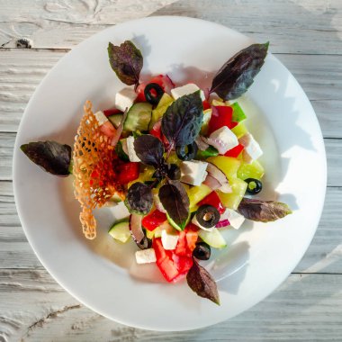 Tahta bir arka planda beyaz bir tabakta sebze salatası.