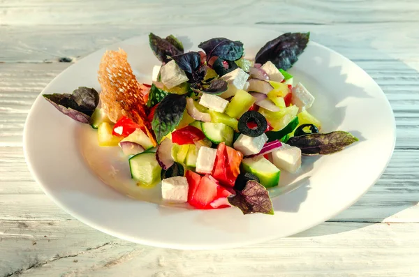 Tahta bir arka planda beyaz bir tabakta sebze salatası.