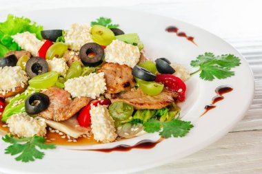 Tahta bir arka planda beyaz bir tabakta sebze salatası.