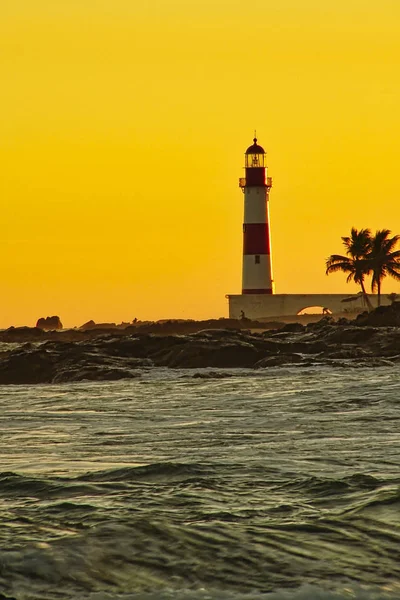 Itapua beach at sunset with lighthouse in background with blue sky with clouds, Salvador, Bahia, Brazil