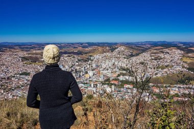 Fotoğrafta dağın tepesindeki kadın Pocos de Caldas - Minas Gerais / Brazil - aşağıdaki şehri izliyor.. 