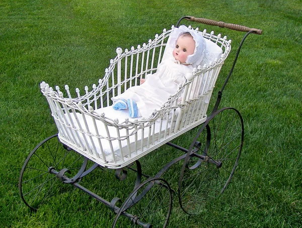 antique baby doll in vintage stroller on grass