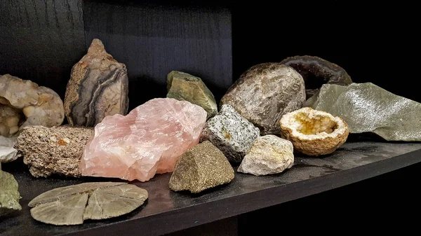 rock collection  with pink quartz on black wooden shelf