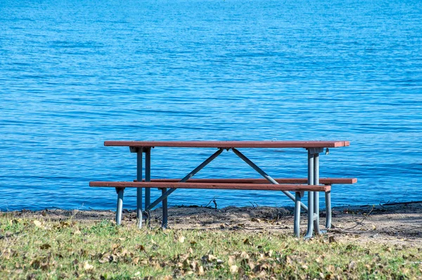 蓝湖水沙草空野餐桌 — 图库照片