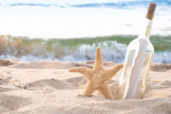 消息在瓶和海星在海滩沙子与海浪背景 — 图库照片