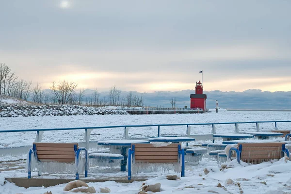 公園のベンチとテーブルに氷で冬のオランダ港赤灯台 — ストック写真