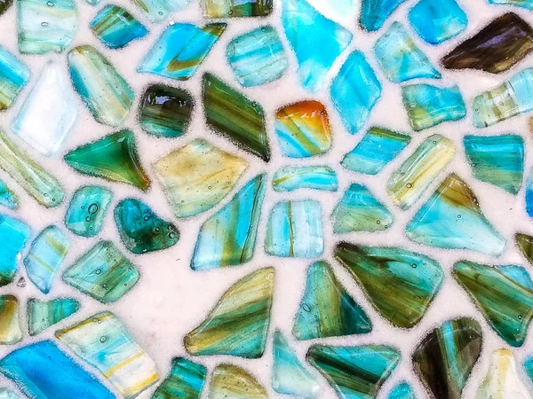 close up of turquoise and green agate stone in mosaic pattern on white background