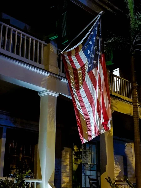 hanging American flag on house porch at night time