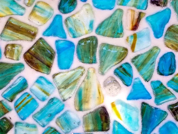 close up of turquoise and green agate stone in mosaic pattern on white background