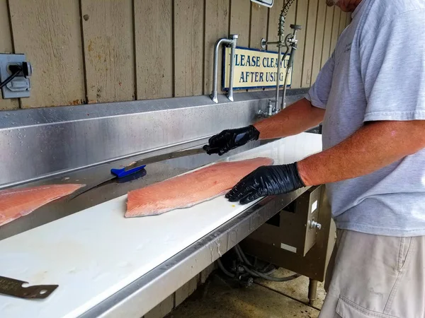 魚のクリーニングステーションカウンターで新鮮なサーモンを詰める男 — ストック写真