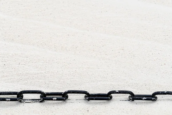 ビーチ砂の黒い金属チェーンのクローズアップ — ストック写真
